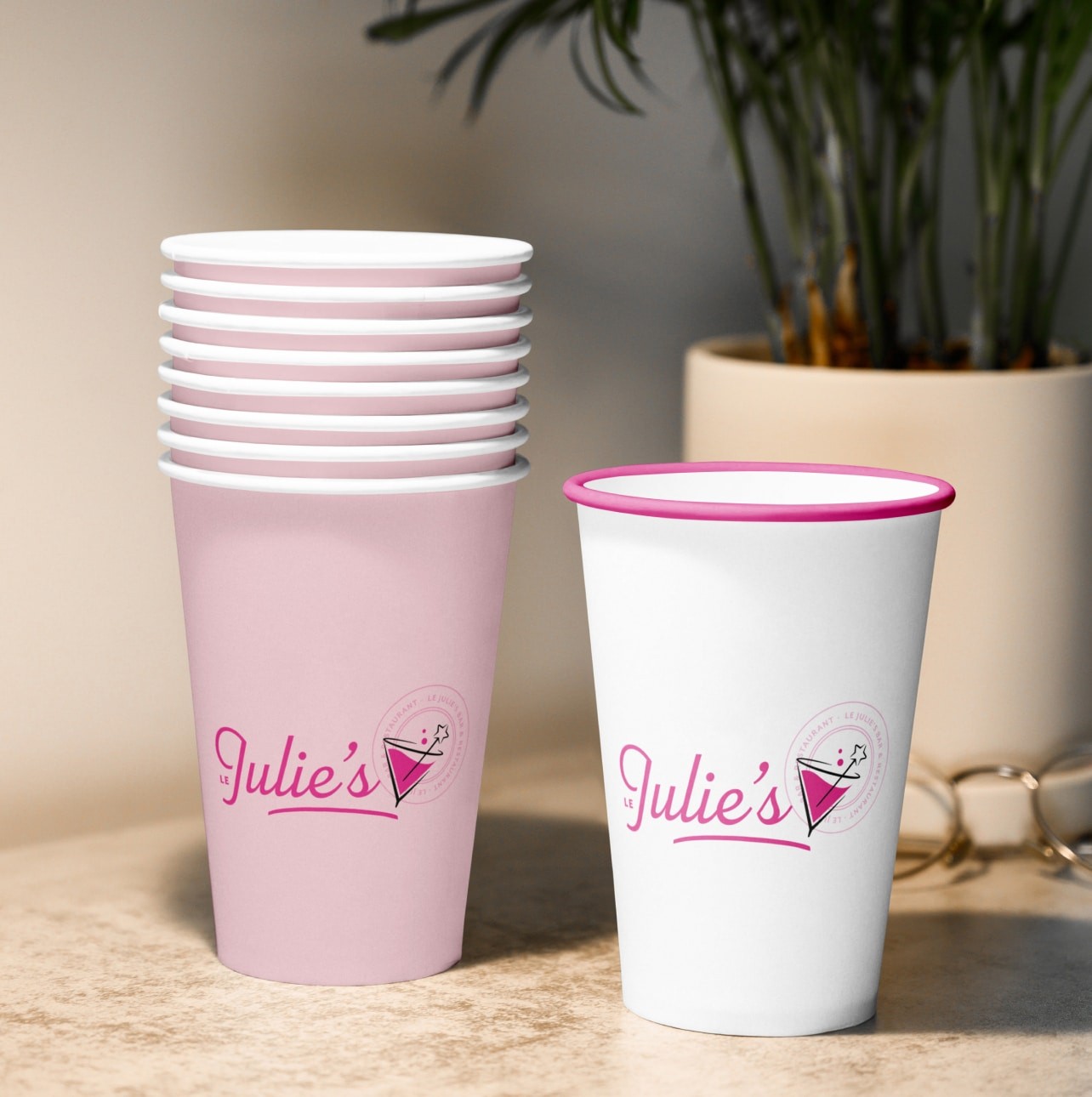 Deux verres en cartons avec le logotype Le Julies d'affichés sur chaque gobelet. L'un est rose l'autre blanc.