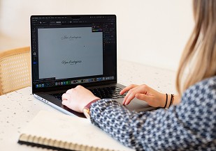 Graphiste travaillant un logo sur son ordinateur, carnet de croquis à côté