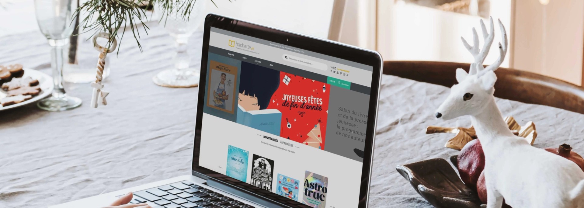 Site internet d’Hachette aux couleurs de Noël sur un ordinateur portable, sur une table de fête