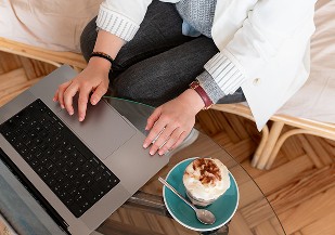 Mains sur un ordinateur portable à côté d'un café, mise en application de l'identité