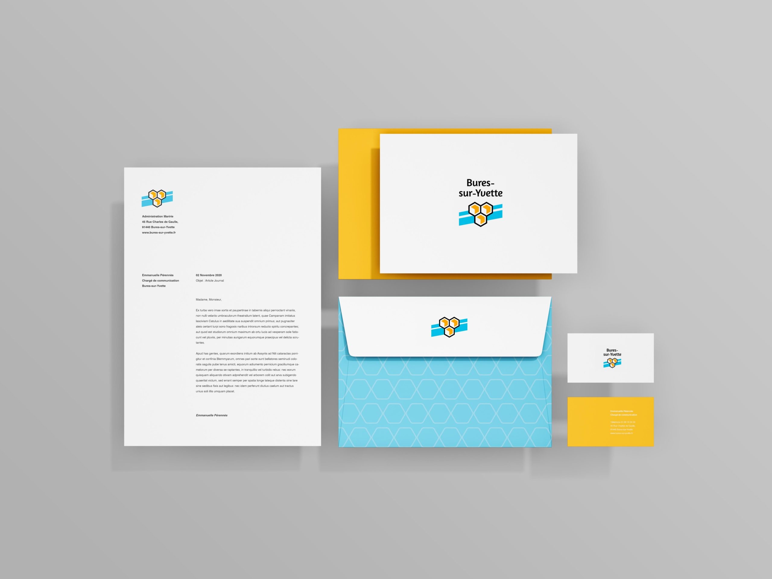 Ensemble des supports de communication de la ville. Une feuille A4 et sa mise en page à gauche, une enveloppe bleue et le logotype au milieu avec un encart A5 et les cartes de visite orange à droite