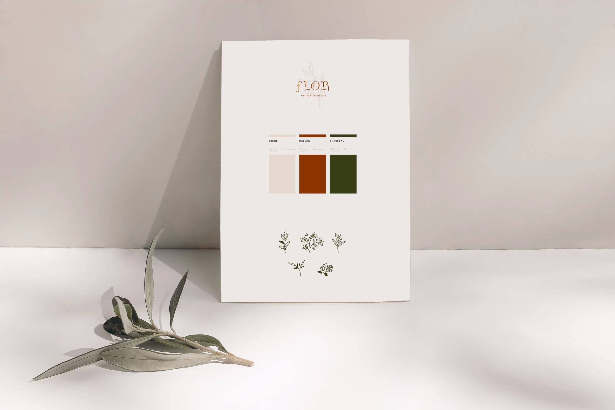 Charte graphique du fleuriste Flor. Feuille blanche posé sur une table avec une feuille posé à gauche. Sur la feuille on retrouve le logotype, les couleurs utilisées et les pictogrammes créés sur-mesure