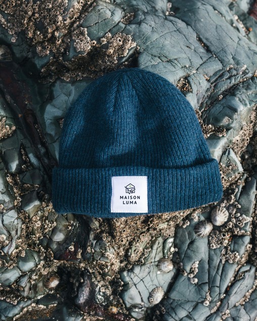 Bonnet bleu à l’étiquette Maison Luma posé sur des rochers
