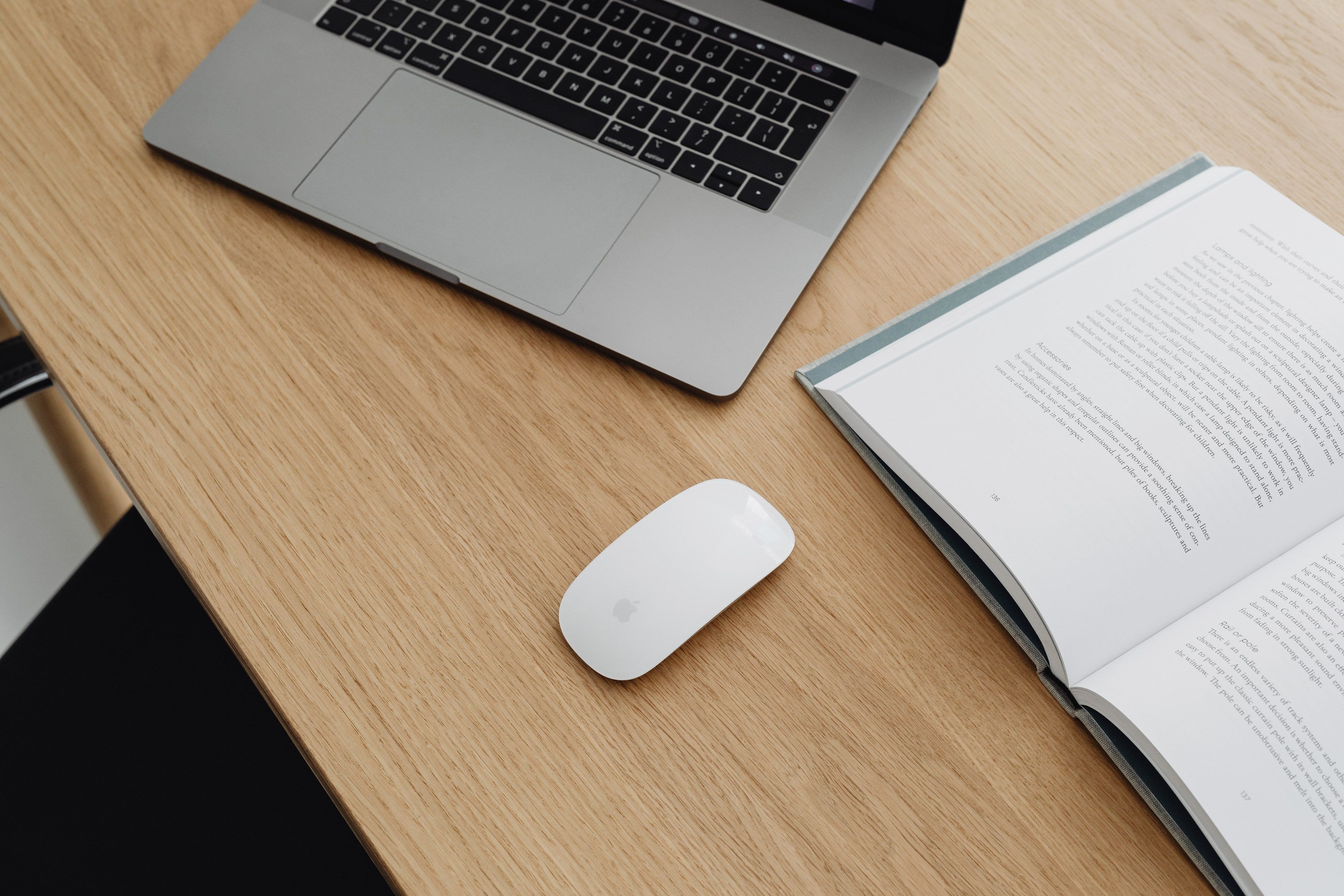 Bureau en bois avec un ordinateur portable, une souris et un livre ouvert