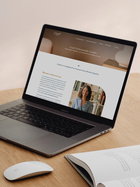 Site internet d'une coach ouvert sur un ordinateur portable, sur un bureau en bois
