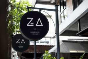 Photo de la devanture du restaurant Za Paris avec le logo blanc dans un encart rond sur fond noir
