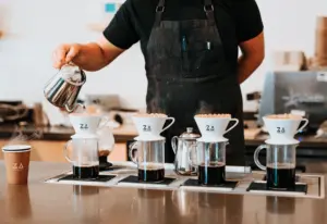 Serveur en train de verser du café dans des tasses ajourées du logo Za Paris