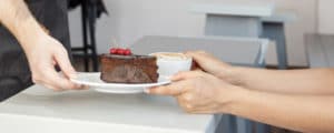 photo de l'intérieur du restaurant avec la main du serveur qui sert un gâteau au chocolat et un café