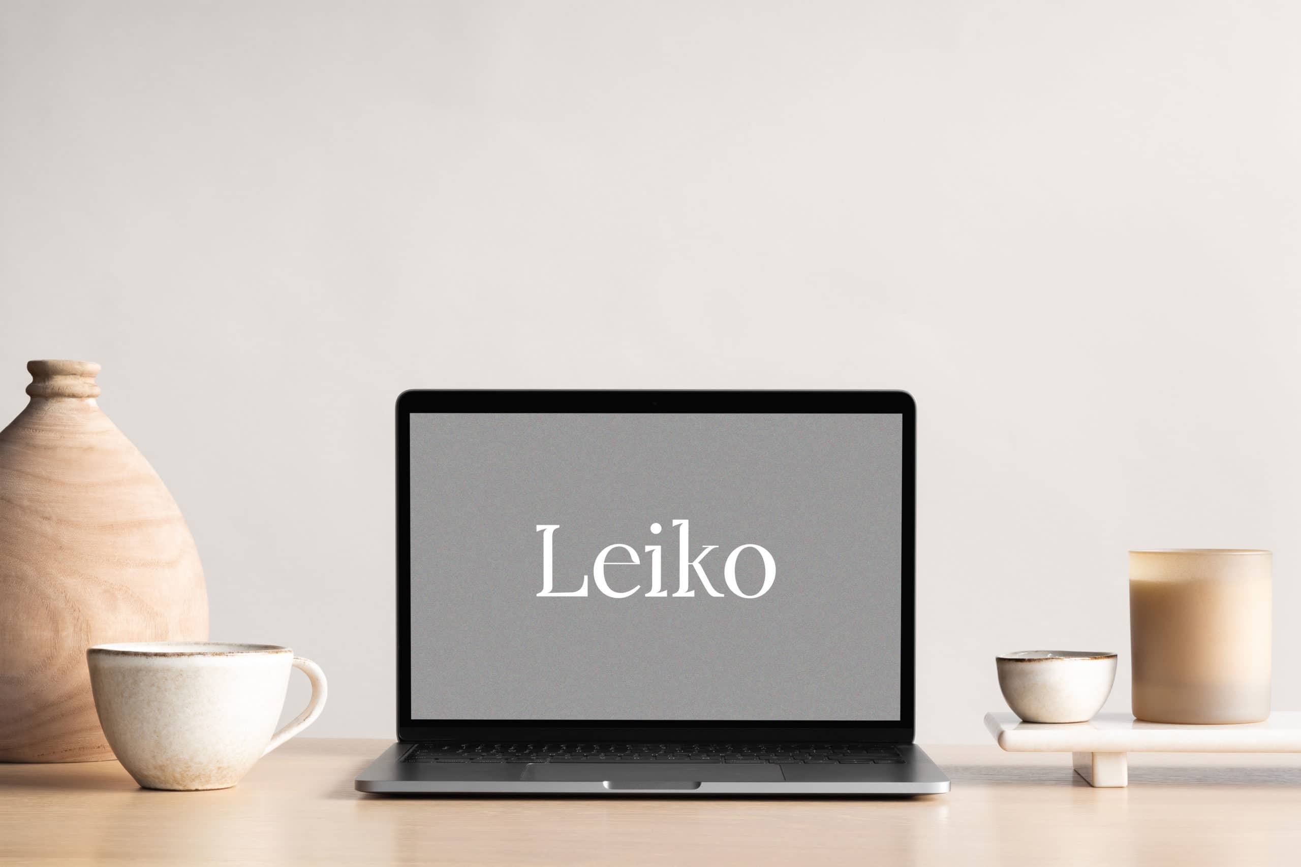 ordinateur posé sur un bureau en bois, à l'interieur de l'ordinateur il y a écrit "Leiko"