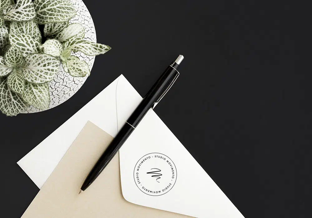 Enveloppe blanche avec le logo du Studio Movimento posée sur une table noire