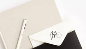 Cahier, enveloppe blanche ajourée du logo Movimento avec un stylo blanc